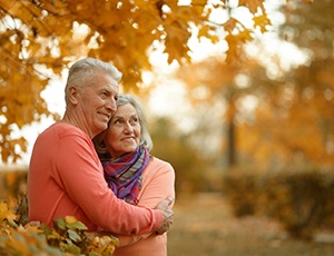An older couple outside enjoying their time together, hugging and smiling 