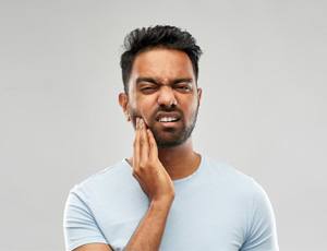 a man touching his jaw due to TMJ disorder