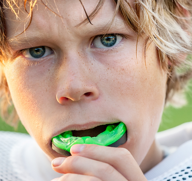 Young boy putting a mouthguard over his teeth