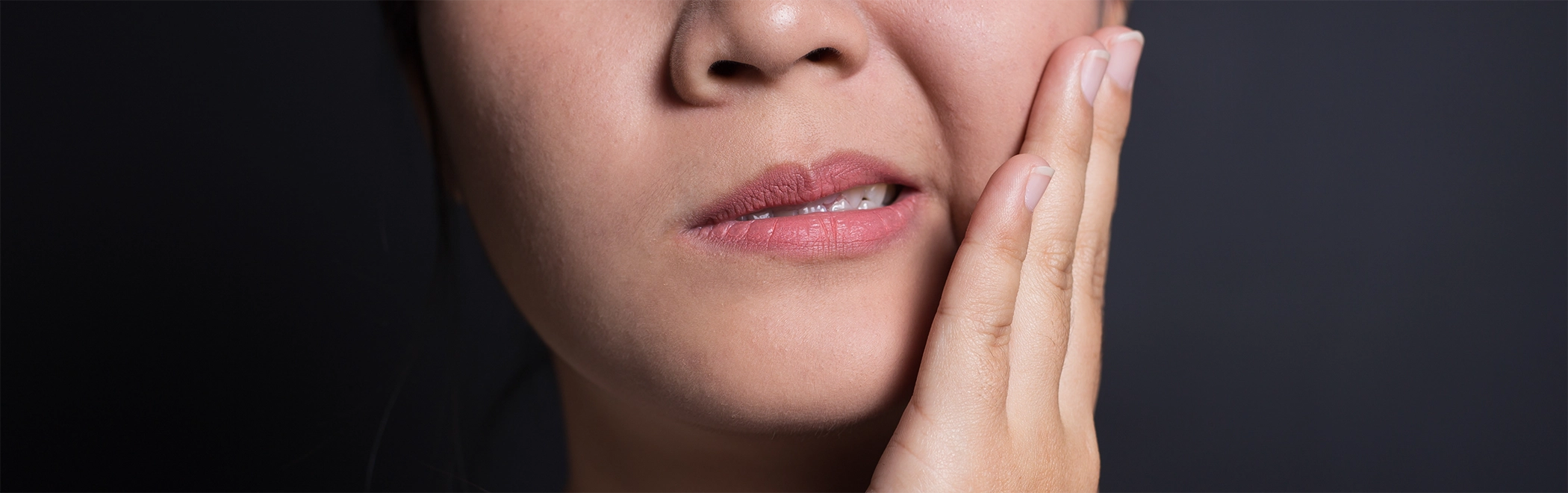 Person holding their cheek in pain