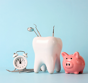 Model of a tooth next to a piggy bank and alarm clock