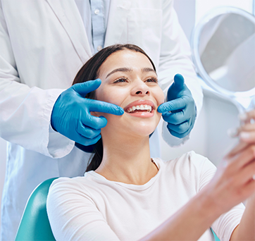 Young woman in the dental chair looking at her smile in a mirror