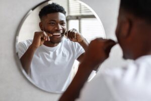 a man flossing and looking in a mirror