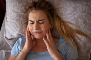 Woman in bed rubbing her toothache